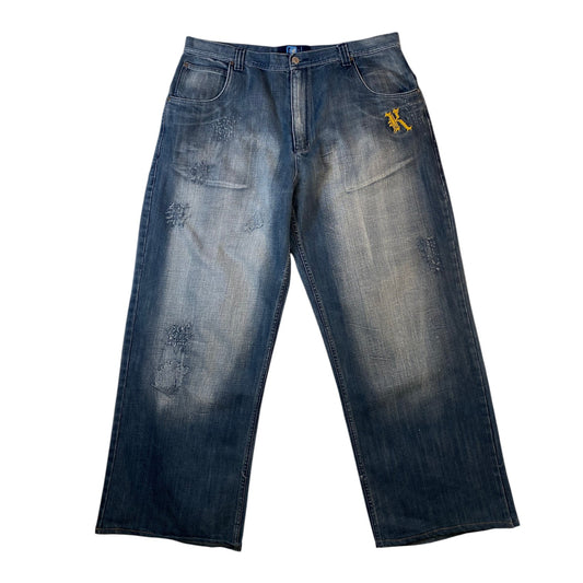 A pair of faded blue denim jeans with a washed-out, distressed finish and a small yellow embroidered logo on the upper right hip, shown flat against a white background.