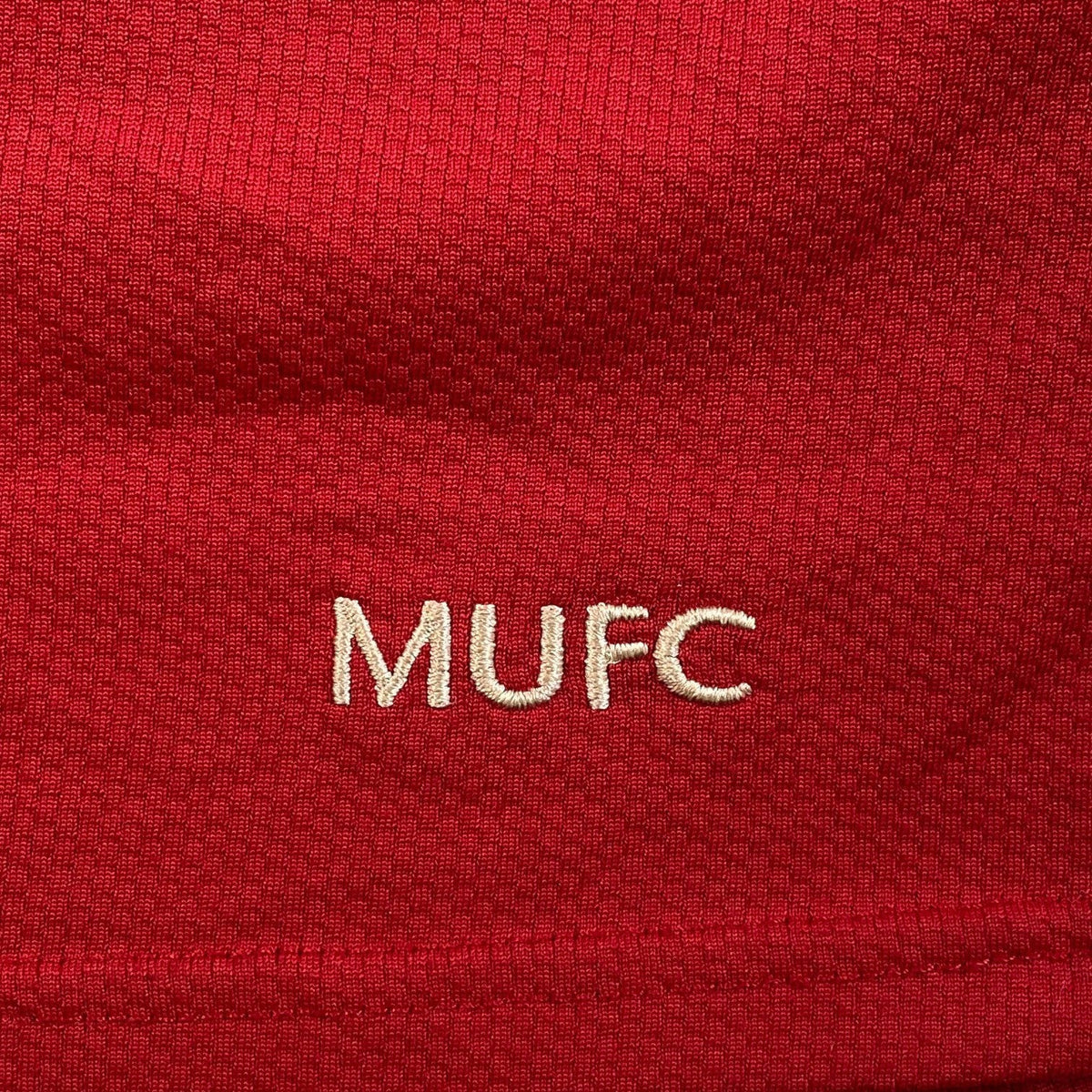Digg It Thrift & Vintage 2006-2007 Manchester United home shirt detail with embroidered white MUFC logo on red fabric