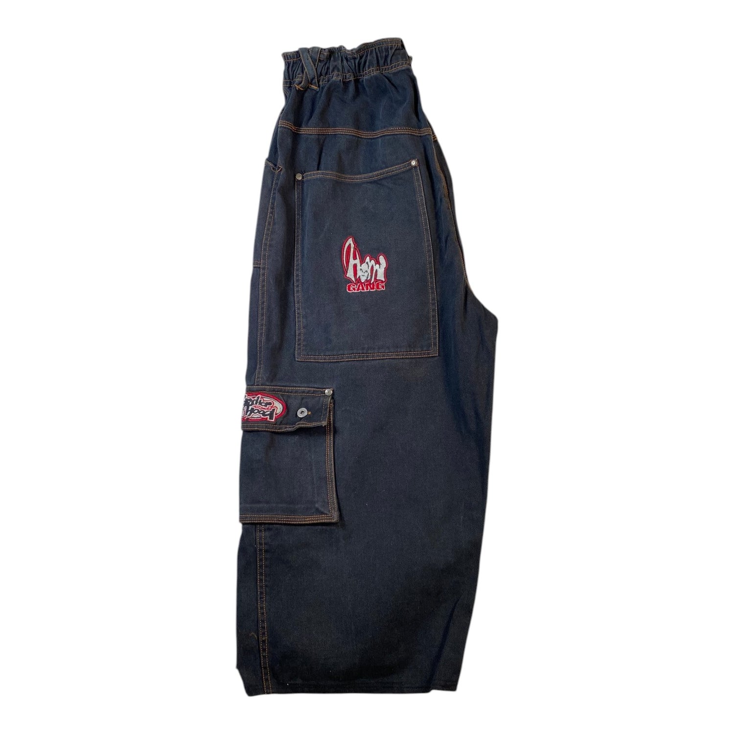 Dark indigo denim bib overalls with a front utility pocket, cargo pocket, and elastic waistband, featuring a red and white embroidered logo on the pocket.