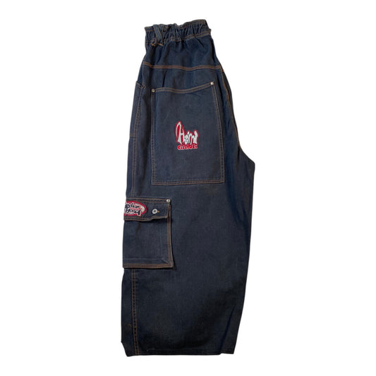 Dark indigo denim bib overalls with a front utility pocket, cargo pocket, and elastic waistband, featuring a red and white embroidered logo on the pocket.