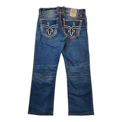 Rusty Brand bootcut jeans in medium blue denim, shown from the back with the signature embroidered horseshoe logo on the back pockets.