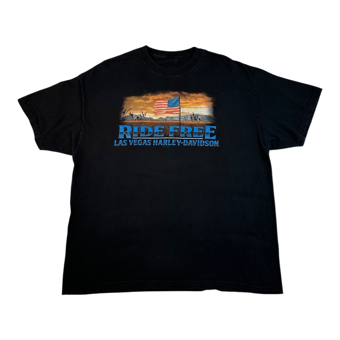 A black short-sleeve graphic t-shirt featuring a vintage-style print with an American flag, desert sunset, and the text 'RIDE FREE LAS VEGAS HARLEY-DAVIDSON' in blue and white.