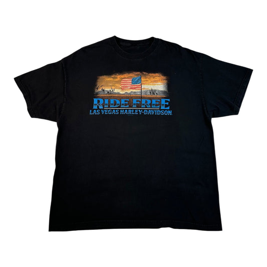 A black short-sleeve graphic t-shirt featuring a vintage-style print with an American flag, desert sunset, and the text 'RIDE FREE LAS VEGAS HARLEY-DAVIDSON' in blue and white.