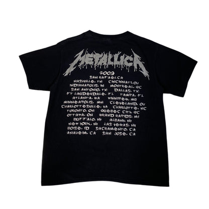 A black short-sleeve Metallica t-shirt showing the back side, which features a large white 'Metallica' logo above a white printed concert tour schedule from San Rafael, 2009.
