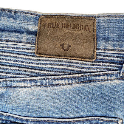 Close-up of the waistband of light blue denim jeans showing a brown leather True Religion brand patch.