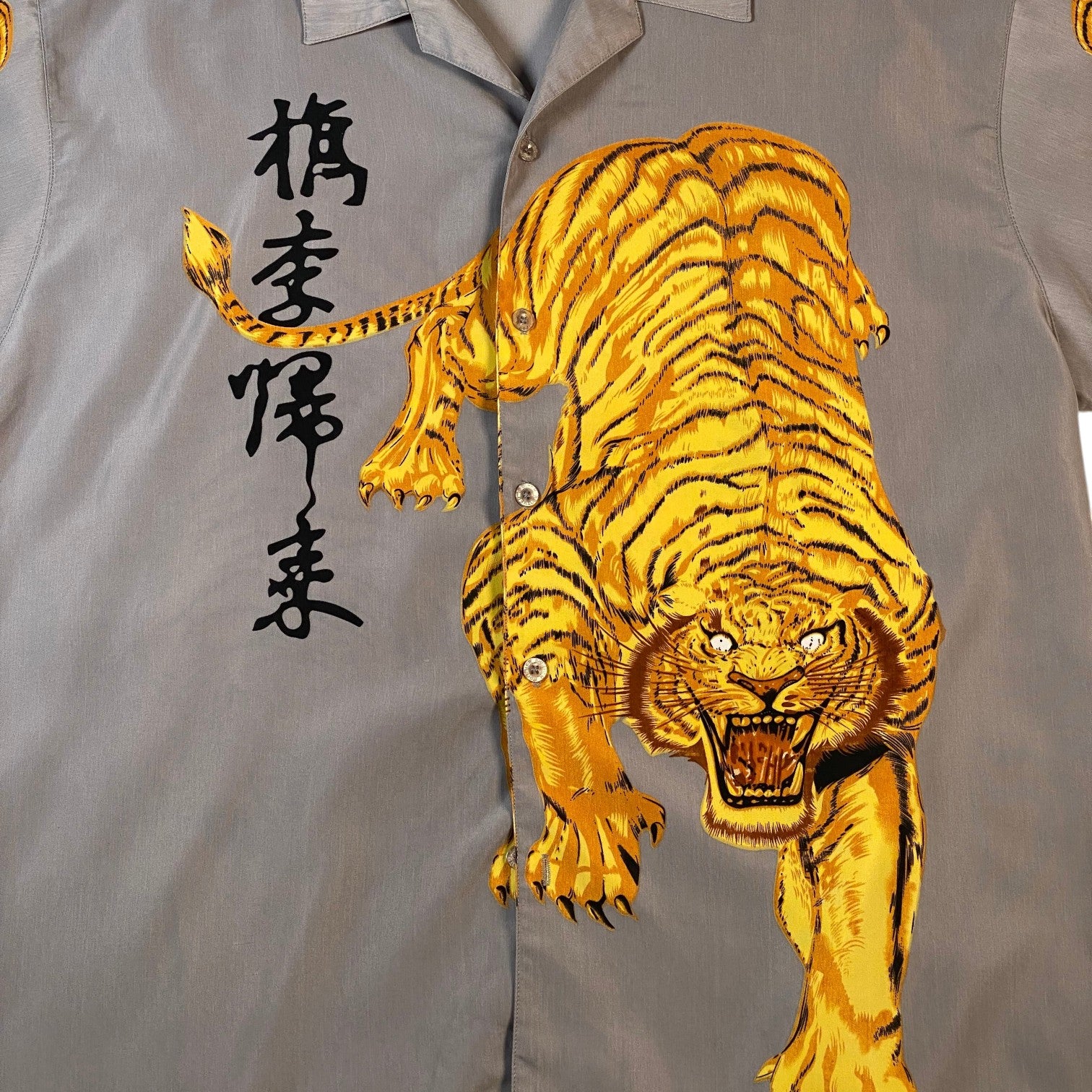 A gray short-sleeve button-up shirt featuring a large embroidered golden tiger and black Japanese characters on the front.