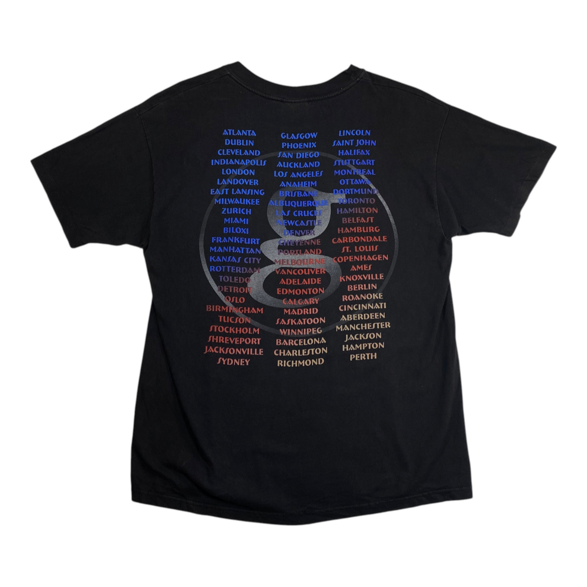 Back of a faded black Digg It Thrift & Vintage Garth Brooks 1990s world tour t-shirt with city names in color