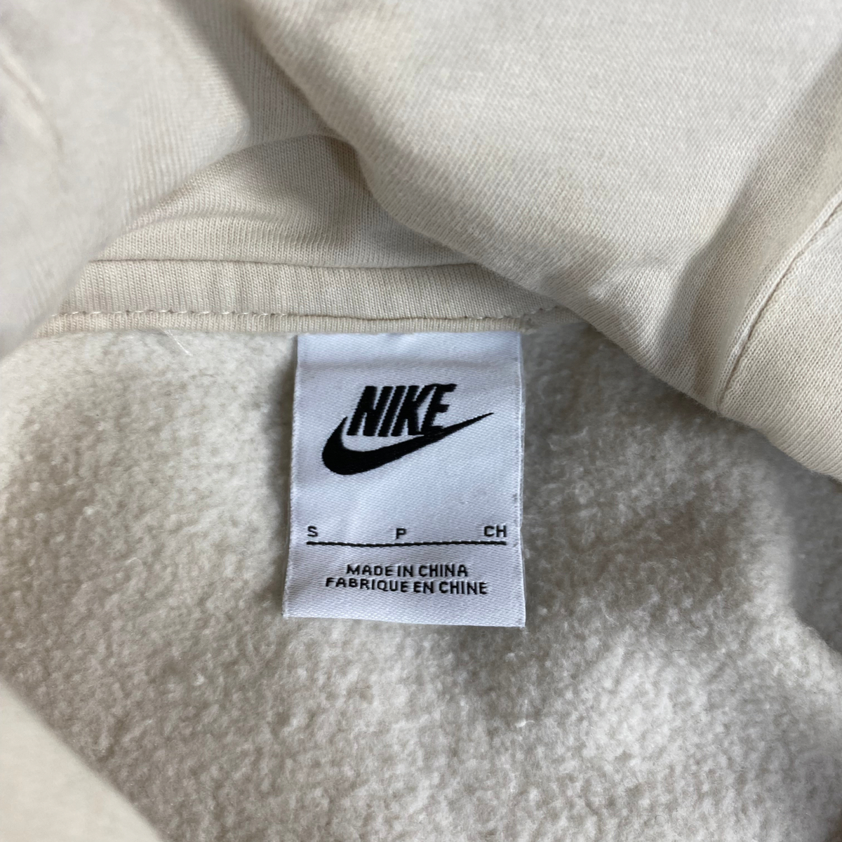 Digg It Thrift & Vintage Nike cream pullover hoodie interior brand tag showing size small and made in China label