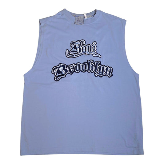 A light blue sleeveless muscle tank top featuring a stylized 'Now Brooklyn' graphic in black and white gothic font across the chest, displayed flat against a white background.