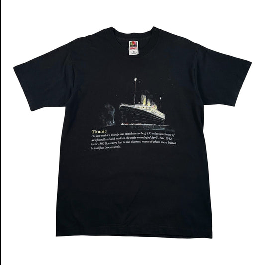 A black short-sleeve crewneck t-shirt featuring a graphic print of the Titanic on the front with a white text description below it, displayed flat against a white background.