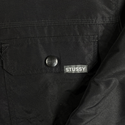Digg It Thrift & Vintage black Stüssy insulated workwear jacket featuring a snap-front pocket and brand logo tag.