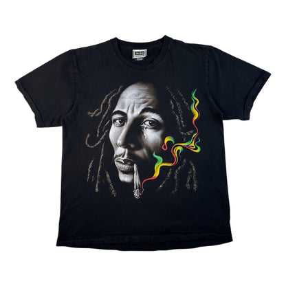 A black short-sleeve crewneck t-shirt featuring a graphic print of Bob Marley's face with a joint in his mouth and colorful green, yellow, and red smoke, shown against a plain white background.