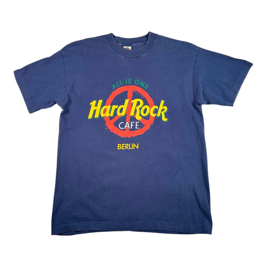 A navy blue short-sleeve t-shirt featuring a colorful graphic on the front with the text 'Hard Rock CAFE' in yellow over a red peace sign, with 'ALL IS ONE' above and 'BERLIN' below.