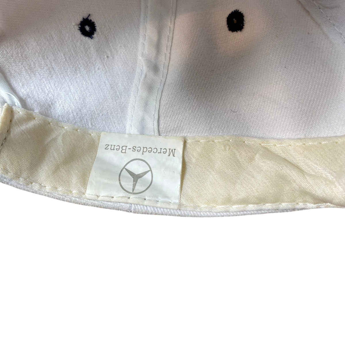 Digg It Thrift & Vintage white baseball cap interior showing Mercedes-Benz logo tag and ventilation eyelets