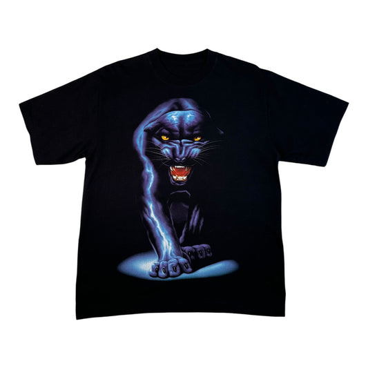 A black short-sleeve graphic t-shirt laid flat on a crinkled light gray surface. The shirt features a large graphic print of a glowing blue panther with yellow eyes and an open mouth showing red teeth.