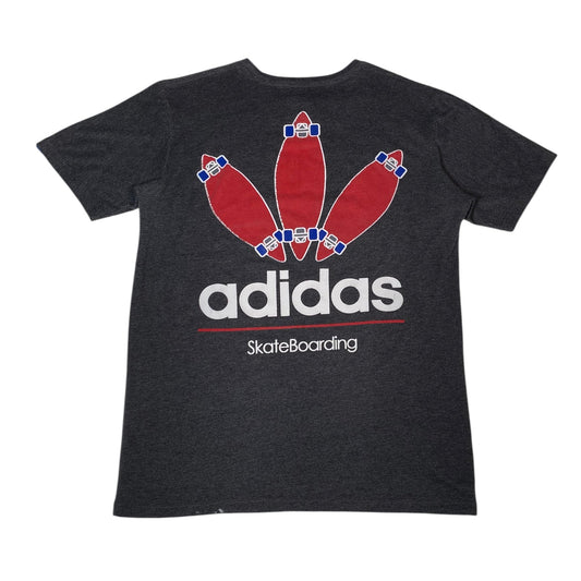 A dark heather gray short-sleeve t-shirt featuring a graphic of three red skateboards arranged like bowling pins, with the white 'adidas' logo and 'SkateBoarding' text underneath.