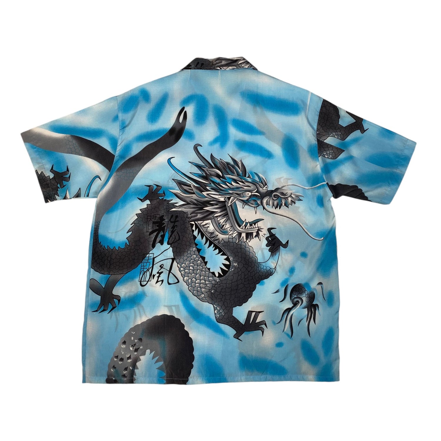 A short-sleeve camp collar shirt featuring a large black and silver dragon design over a blue and white marbled background, displayed flat against a white background.
