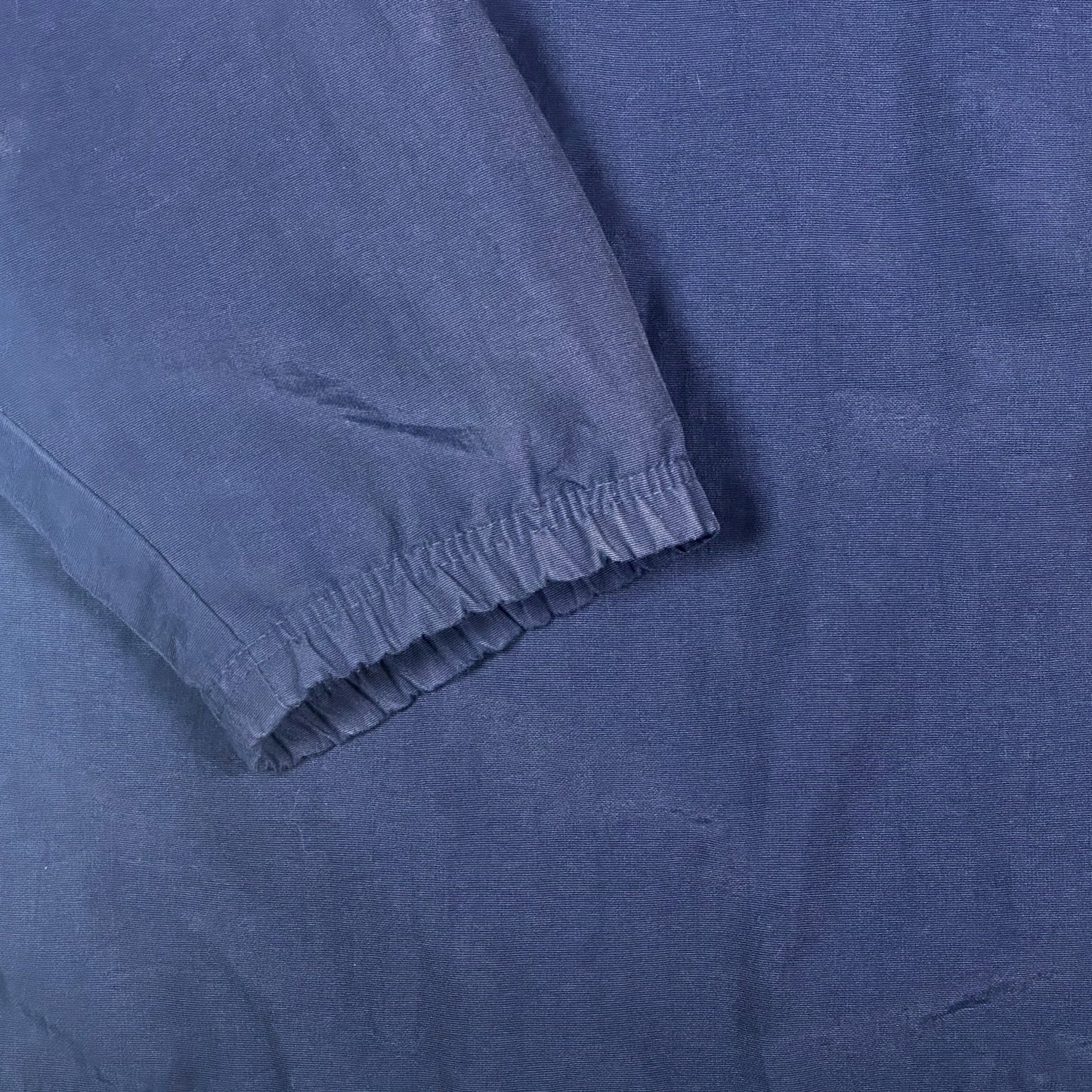 Close-up of navy blue fabric sleeve with elastic cuff from a Digg It Thrift & Vintage Adidas coach jacket
