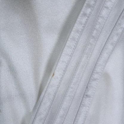 Close-up of white Adidas Chile Rasta track jacket fabric by Digg It Thrift & Vintage showing a small light stain.